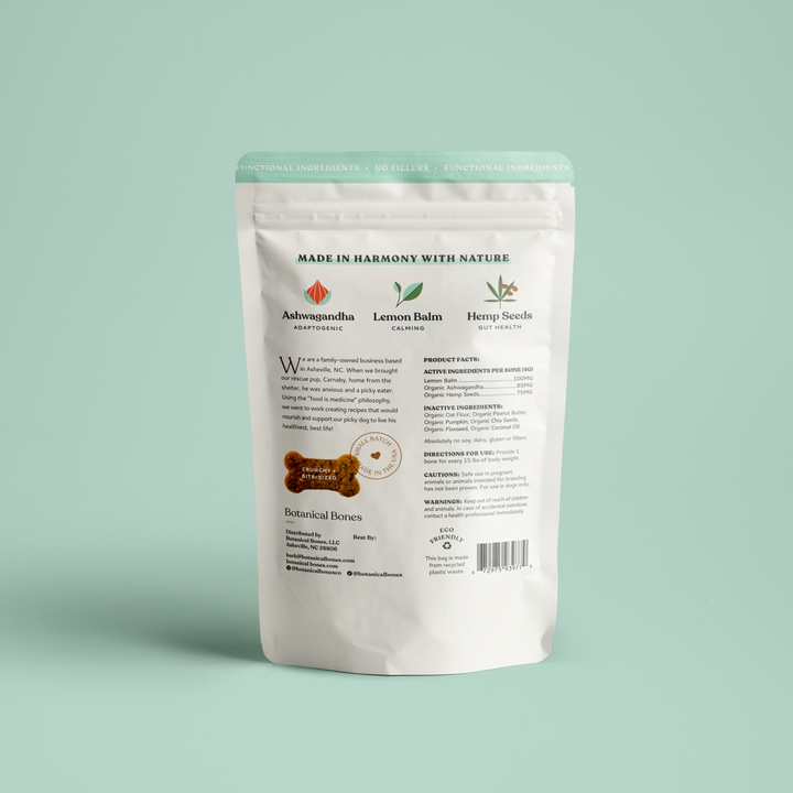 The back of a Botanical Bones Balance + Calm dog treat pouch, detailing ingredients such as Ashwagandha for adaptogenic properties, Lemon Balm for calming effects, and Hemp Seeds for gut health. The packaging highlights eco-friendly practices and small-batch production, perfect for conscious dog owners focused on natural and organic dog wellness products.